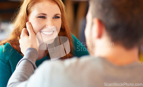 Image of Couple, touch and woman with smile in cafe, relax and happiness for peace in relationship. Adult, female person and girl with man or partner with hand on face in coffee shop and joy in date with guy