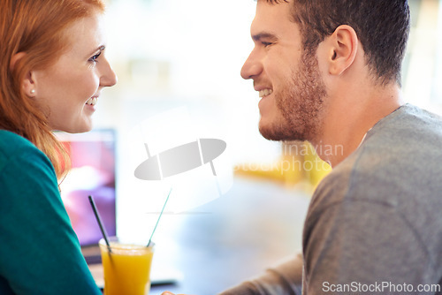 Image of Happy couple, smile and eye contact in cafe with love, romance and affection on anniversary date. Romantic, man and woman in restaurant bonding with juice, beverage and laughter in relationship