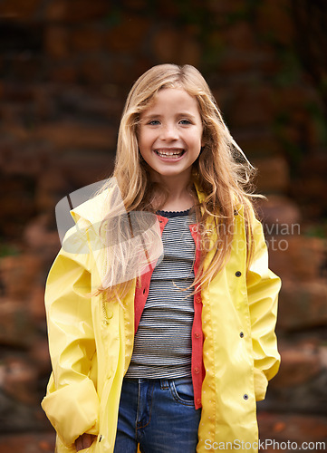 Image of Portrait, smile and happy girl in raincoat, winter and outdoors for cold weather. Child, joyful or relax in nature for autumn or rain on vacation in Scotland, holiday or outside for youth or travel