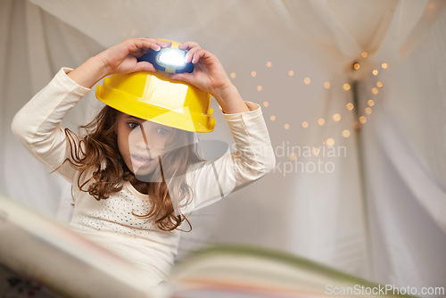 Image of Girl, child and book for reading with lamp, below and learning with thinking for education in family home. Kid, story and study with light on helmet, language or literacy skills with blanket in house