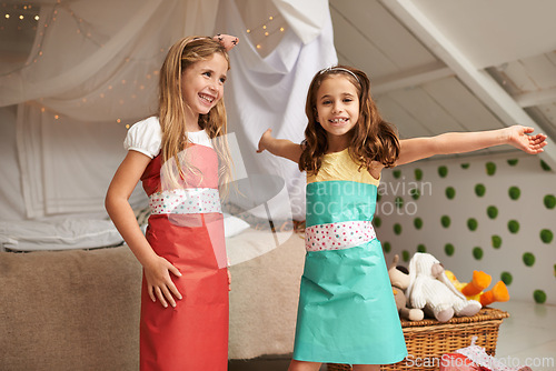 Image of Fashion, paper and portrait of children with dress for fun, show or playing together at home. Happy, smile and young girl kids in gift wrap outfit for style with bonding in bedroom at house.