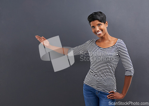 Image of Happy woman, portrait and presentation with advertising or marketing on a gray studio background. Female person or Indian with smile for notification, alert or special deal on fashion or mockup space