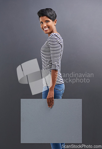 Image of Happy woman, portrait and presentation with billboard for marketing or advertising on a gray studio background. Young female person or Indian with smile, poster or sign for message on mockup space