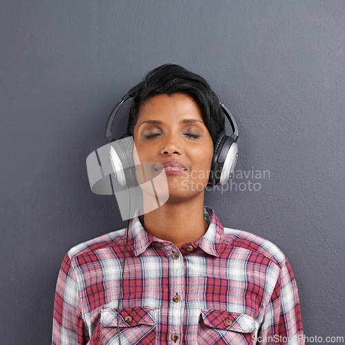 Image of Woman, relax and listening with headphones for music or podcast on a gray studio background. Calm, young female person or Indian with smile or enjoying audio sound track with headset on mockup space