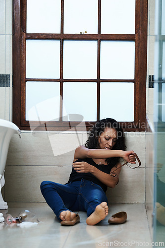 Image of Woman, drug addict and floor in bathroom for addiction or disorder, depression and mental health. Person or user, relapse and belt for heroin overdose or substance abuse for feeling of euphoria.