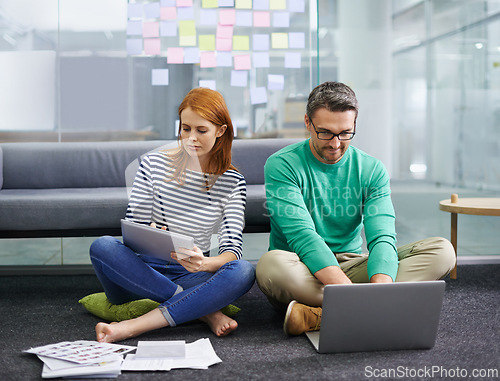 Image of Woman, man and laptop on floor at startup with tablet, documents and thinking with teamwork in office. Business people, partnership and computer with paperwork for planning at creative media agency