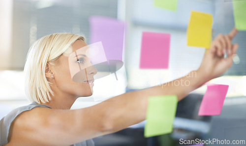 Image of Woman, glass and board with pointing, thinking and notes for planning, proposal and idea development. Person, wall and paper for brainstorming process, decision or choice with smile in modern office