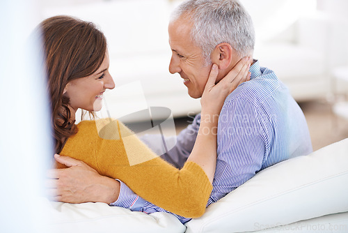 Image of Couple, happiness and affection on sofa in living room together for healthy relationship, bonding and love. Smile, mature man and woman in lounge for romance, embrace and relaxing in apartment