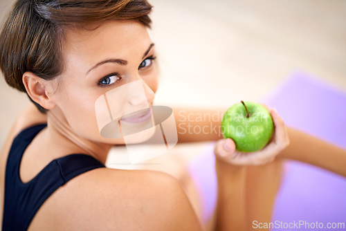 Image of Portrait, exercise and happy woman with apple in gym for diet, nutrition and wellness with healthy body. Face, fitness and person eating fruit for vitamin c or benefits of organic food on yoga mat