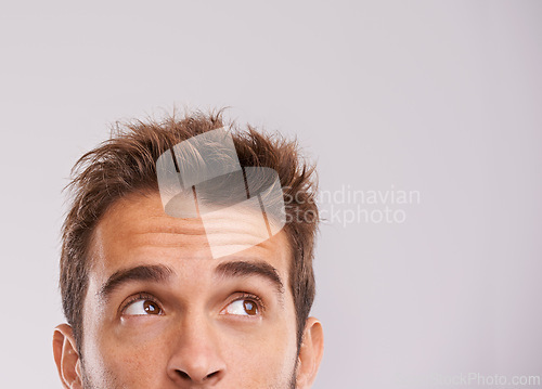 Image of Mockup, eyes up and man with thinking for information, promotion and presentation in studio. Male person, idea and vision on white background for inspiration, daydreaming or thoughtful direction