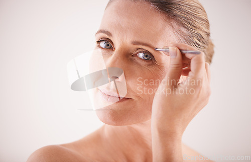 Image of Eyebrows, tweezer and portrait of model on a white background for facial grooming or hair removal. Beauty, salon and face of mature female person isolated in studio plucking or tweezing for skincare