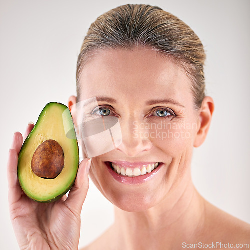 Image of Skincare, avocado and portrait of mature woman in studio for health, wellness or natural face routine. Smile, beauty and female person with organic fruit for dermatology treatment by white background