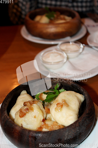 Image of Varenyky with fried slices of bacon in wooden plate