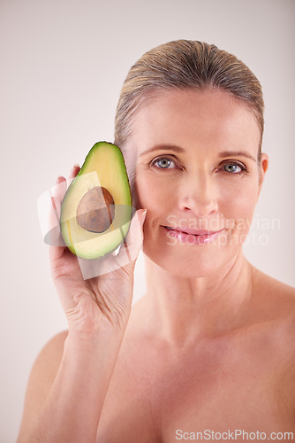 Image of Beauty, avocado and portrait of mature woman in studio for health, wellness or natural face routine. Smile, skincare and female person with organic fruit for dermatology treatment by white background