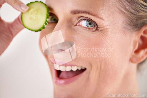 Image of Skincare, cucumber and portrait of mature woman in studio for health, wellness or natural routine. Smile, beauty and female person with organic vegetable for dermatology treatment by gray background.