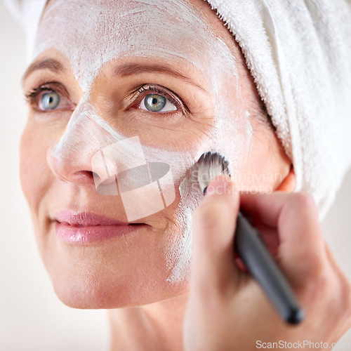 Image of Mature woman, face mask and brush with happiness in studio for skincare or anti aging on self care, wellness and fresh skin. Closeup, female person and glow with smile for facial and beauty or luxury