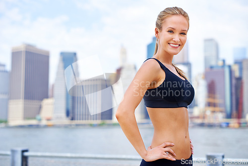 Image of Woman, city and confident at river in sportswear with break for walk, fitness and healthy mindset in New York. Portrait, female person and smile with self care in summer, hot weather and happy