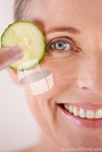 Image of Skincare, cucumber and portrait of woman in studio for health, wellness or natural facial routine. Smile, beauty and mature person with organic vegetable for dermatology treatment by white background