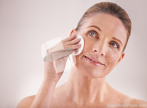 Image of Mature woman, smile and cotton for skincare in studio with facial cleansing, cosmetics and skin treatment. Model, person and swab for face detox, makeup removal and natural beauty on white background