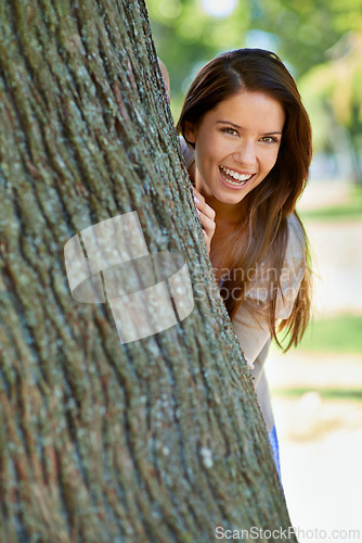 Image of Woman, park and tree with hide, smile and portrait with happiness and green fun for nature. Lady, laugh and sun with grass, forest and happy for excited playful summer with optimism and sunshine