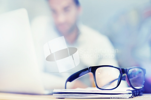 Image of Blur, notebook and glasses on desk with man in office for planning, schedule and agenda on table. Laptop, eyewear or worker copywriting with diary journal for business, administration or email on web