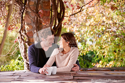 Image of Spring, relax and couple embrace with coffee cups on table in nature, environment and together for romance. Partners, woman and man with hand from girl, hug and touch for love in marriage and park