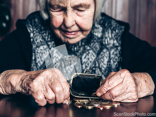 Image of Portrait of an old woman counting money. The concept of old age, poverty, austerity.