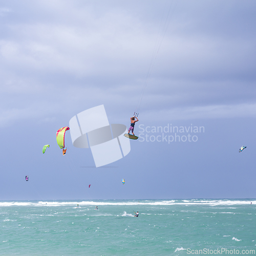 Image of Kiteboarding. Fun in the ocean. Extreme Sport Kitesurfing. Kitesurfer jumping high in the air performing triks during kitesurfing session.