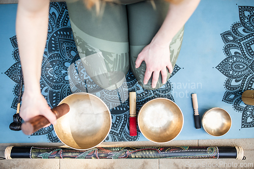 Image of Yoga concept, meditation and sound therapy. Beautiful young caucasian woman surrounded by copper tibetan singing bowls and instruments.