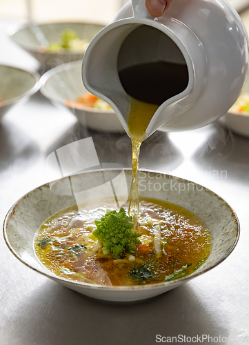 Image of Pouring broth on fresh salad