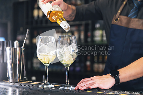 Image of Bartender pours ingredients into glasses