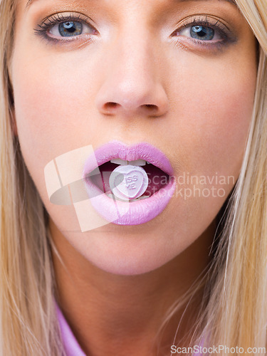 Image of Woman, closeup and studio portrait with candy in mouth for makeup, lipstick and heart sign for kiss. Girl, person and model for beauty with sweets, emoji and zoom of face for eating with cosmetics