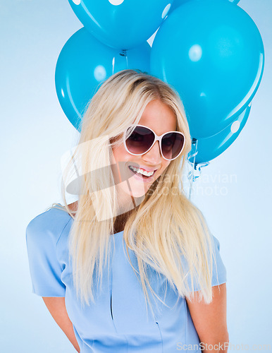 Image of Woman, balloons and smile in studio with sunglasses for event, party or celebration by blue background. Girl, person or model with glasses, happy and excited with fashion, trendy style or birthday