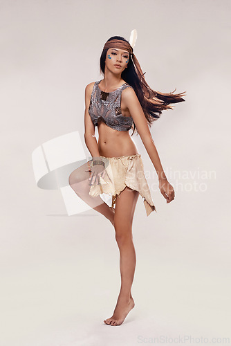 Image of Performance, dancing and Native American woman in studio with warrior makeup, confidence and tribe style. Indigenous fashion, face paint and proud girl in First Nations clothes on white background