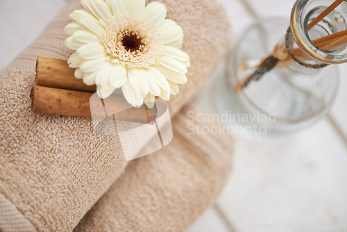 Image of Flower, cinnamon stick and towels for aromatherapy at spa, incense and spices for holistic healing. Top of tools for treatment, stress relief and self care with natural ingredients and glass bottle