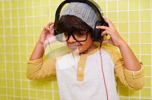 Image of Child, music and glasses with headphones in bathroom with song in a home. Radio, eyewear and youth fashion with a hipster boy listening to audio with with cool style in a house with spectacle frames