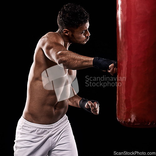 Image of Boxing, man and training in studio with punching bag for workout, exercise or competition fight with fitness. Athlete, boxer and confidence for martial arts with power and topless on black background