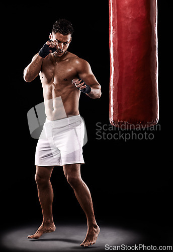 Image of Fitness, punching bag and man boxer in studio for body, training or performance on black background. Fighter, impact and topless male athlete with martial arts, mama or kickboxing match practice