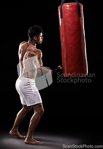 Image of Practice, boxer and man with punching bag in studio with gloves for training with strength and muscle. Adult, athlete and male person in dark background, healthy and power with body, job and sport