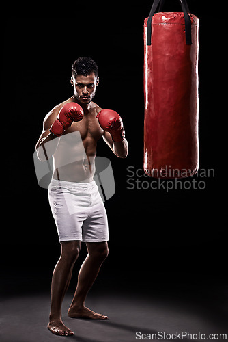 Image of Portrait, boxing bag and gloves for male boxer, studio and athlete on black background. Dark, training and combat sports or MMA for man model, workout, muscle and impact activity for martial arts