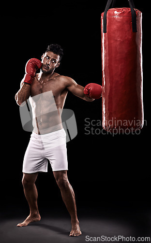 Image of Studio, athlete and man with punching bag and gloves for training with strength and muscle. Adult, boxer and male person in dark background, healthy and power with body for sport and serious for job