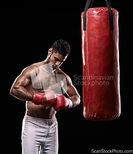 Image of Hands, boxing bag and gloves for male boxer, studio and athlete on black background. Dark, training and combat sports or MMA for man model, workout, muscle and impact activity for martial arts