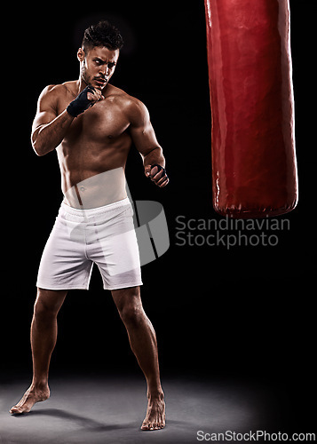 Image of Kickboxing, man or training in studio with punching bag for workout, exercise or competition fight with fitness. Athlete, boxing or serious for martial arts with muscle or topless on black background