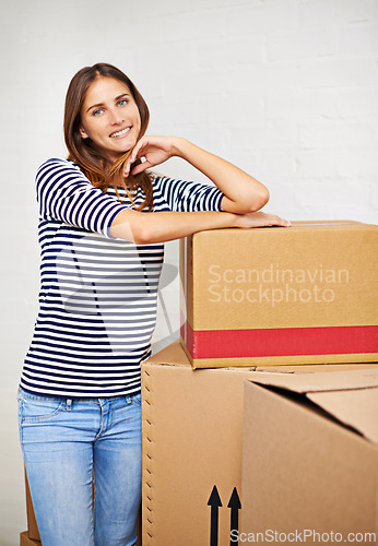 Image of Moving, boxes and portrait of woman in new home, estate or apartment for property. Happy, smile and confident young female person with cardboard package for equipment and products in modern house.