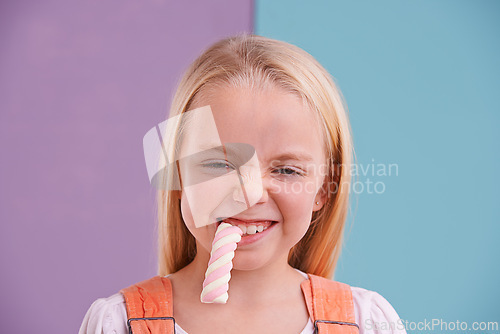 Image of Studio, girl and candy with marshmallow, dessert and hungry for snack and childhood. Child, sweets and yummy food for tasty, eating and happiness on vibrant split pastel pink and blue background