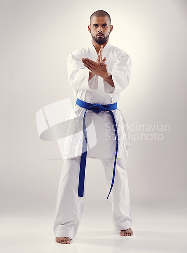 Image of Studio, karate and black man training for power for physical health with fitness and effective technique. White background, male person and adult with disciple of martial arts, sport and blue belt