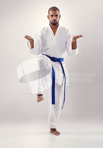 Image of Studio, karate and African man training to improve physical health with fast and effective technique. White background, male person and adult with disciple of martial arts, sport and blue belt