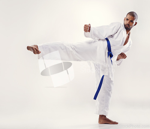 Image of Man, kick and karate fighter in studio, fitness and martial arts on white background. Black male person, athlete and blue belt for taekwondo, discipline and warrior ready for self defense or battle