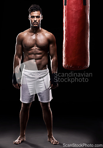 Image of Studio, boxer and portrait of man, punching bag and gloves for training with strength and muscle. Adult, athlete and male person in dark background, healthy and power with body, job and sport