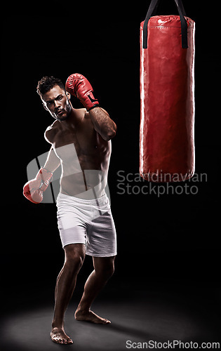 Image of Boxing, man and training in studio with punching bag for workout, exercise or competition fight with fitness. Athlete, boxer and confidence for martial arts with energy or topless on black background